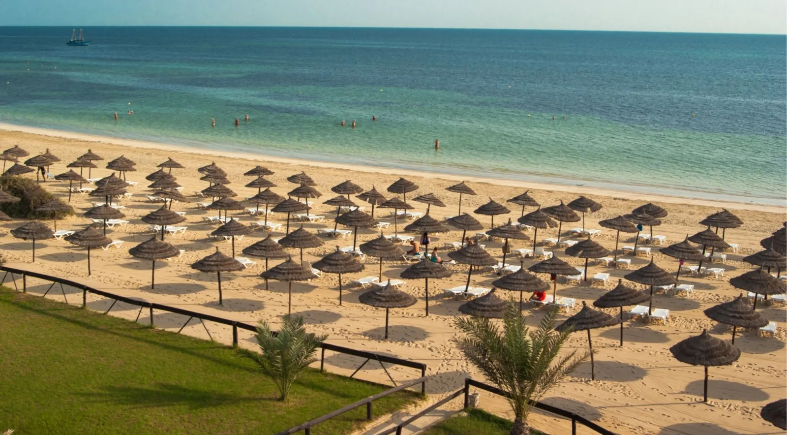 Rows of straw parasols on a Djerba beach above a turquoise sea