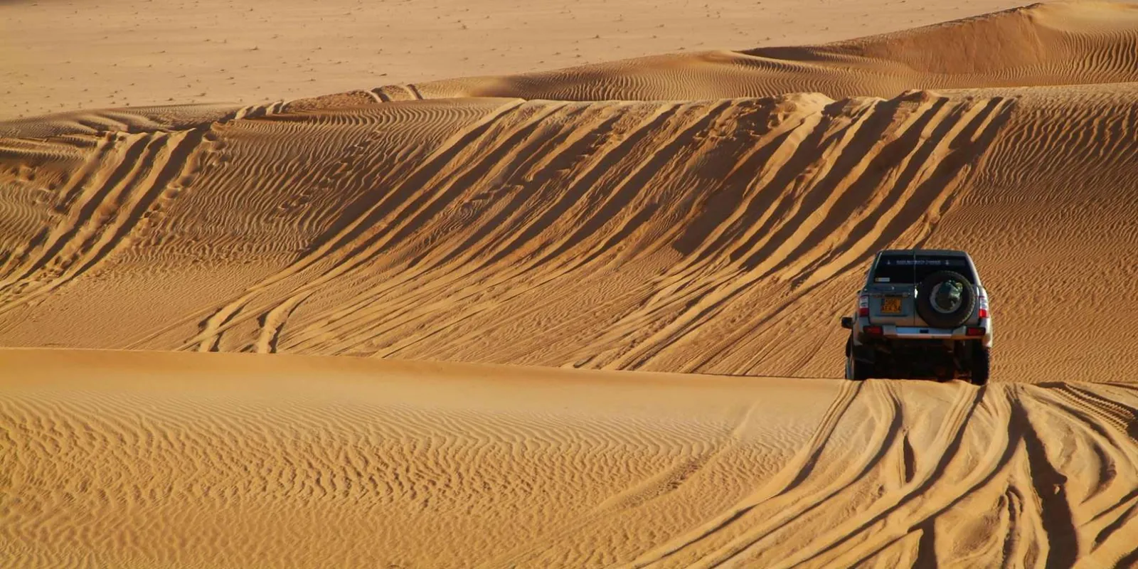 A 4x4 crossing wind-carved dunes on the run to Ksar Ghilane