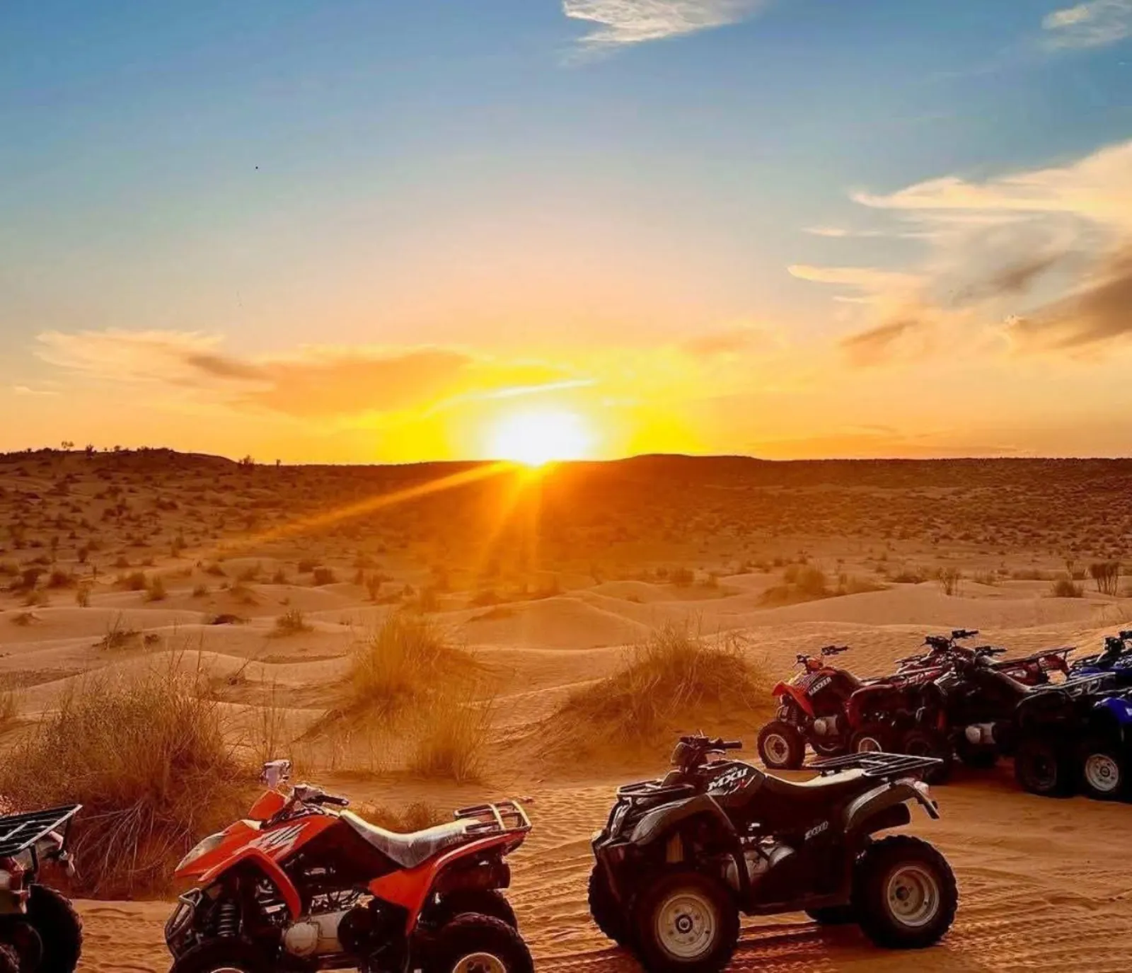 Quad bikes lined up on the sand at sunset